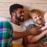 two men holding a baby