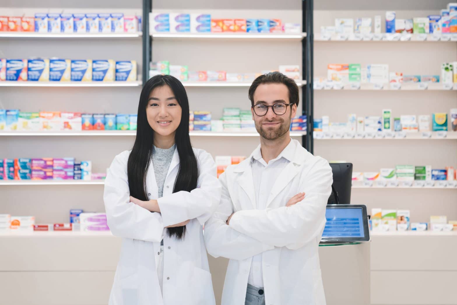 Two Pharmacists standing in front of medication shelves within the pharmacy
